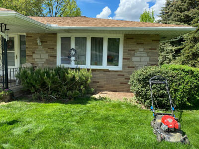 Before fresh plants and new mulch in a flowerbed along the front of a house maintained by Chestnut Landscaping