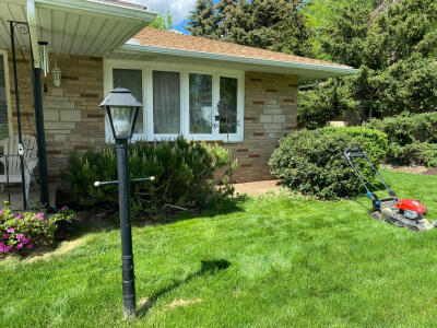 Before fresh plants and new mulch in a flowerbed along the front of a house maintained by Chestnut Landscaping